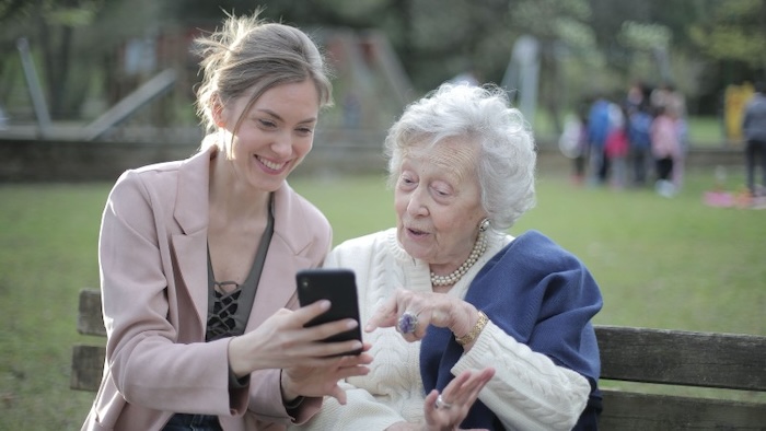 A middle age lady shows her mother a mobile phone.